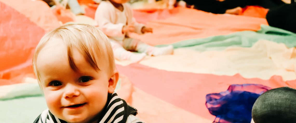 baby sat on parachute smiling to the camera